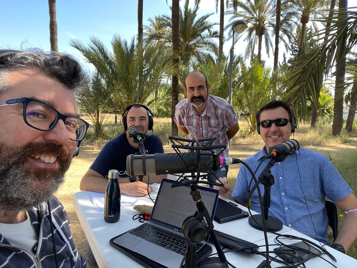 Los cuatro integrantes del podcast, en una mesa con micrófonos, durante la mítica grabación en el palmeral chico de Santiago y Zaraiche (Murcia)